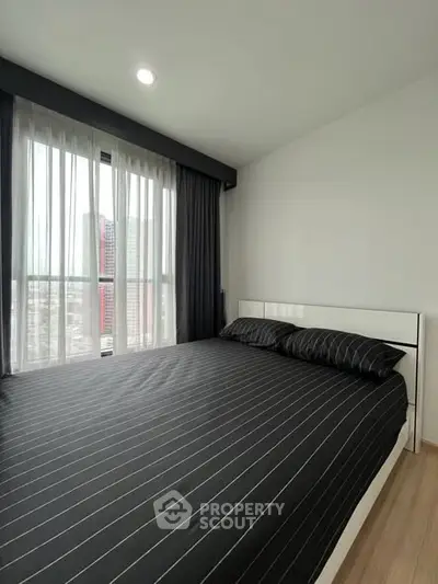 Modern bedroom with large window and city view, featuring sleek black bedding and minimalist design.