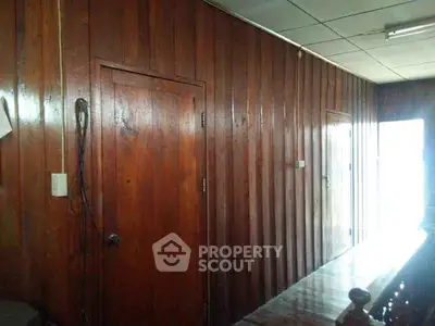 Wood-paneled hallway with natural light and wooden doors, showcasing rustic charm and warmth.