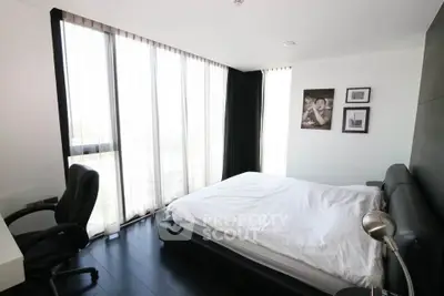 Modern bedroom with large windows and sleek furnishings in a stylish apartment.