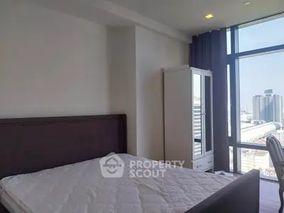 Modern bedroom with large window and city view, featuring a stylish bed and wardrobe.