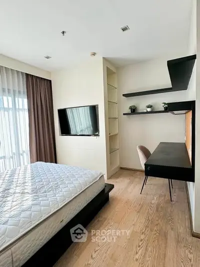 Modern bedroom with sleek desk and wall-mounted TV, featuring natural light and elegant decor.