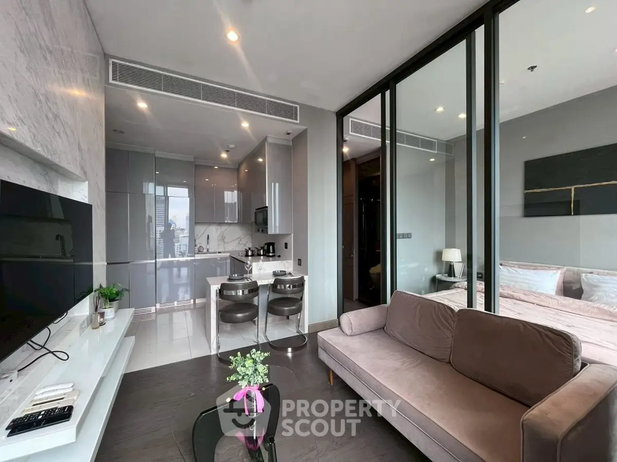 Modern open-plan living room with sleek kitchen and cozy bedroom in luxury apartment.