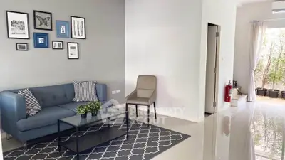 Modern living room with stylish decor and natural light, featuring a blue sofa and elegant wall art.