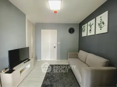 Modern living room with sleek gray sofa and wall-mounted TV, perfect for cozy relaxation.