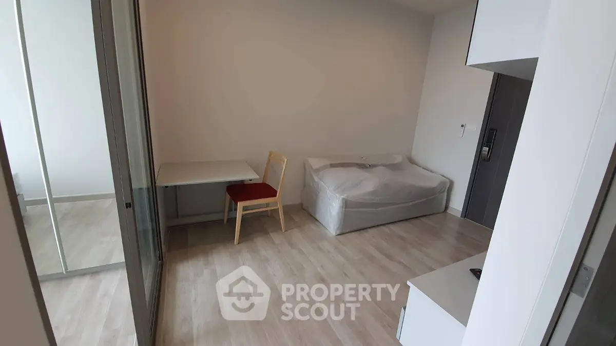 Modern minimalist room with light wood flooring and compact furniture setup.