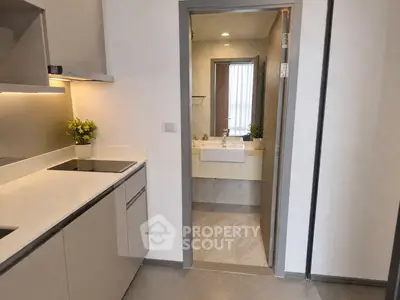 Modern kitchen with sleek design leading to a stylish bathroom, featuring contemporary fixtures and neutral tones.