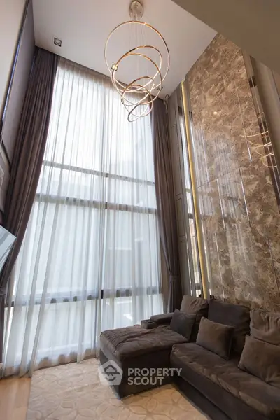 Luxurious high-ceiling living room with elegant chandelier and plush sofa