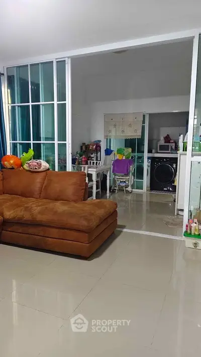 Spacious living room with sliding glass doors leading to a cozy kitchen area, featuring modern appliances.
