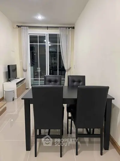 Modern dining area with sleek black furniture and large window for natural light.