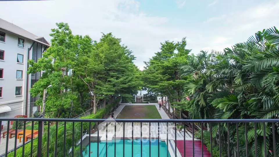 Stunning view of lush greenery and pool from a balcony in a modern residential complex.