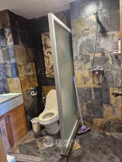 Stylish bathroom with stone tile walls and modern shower design