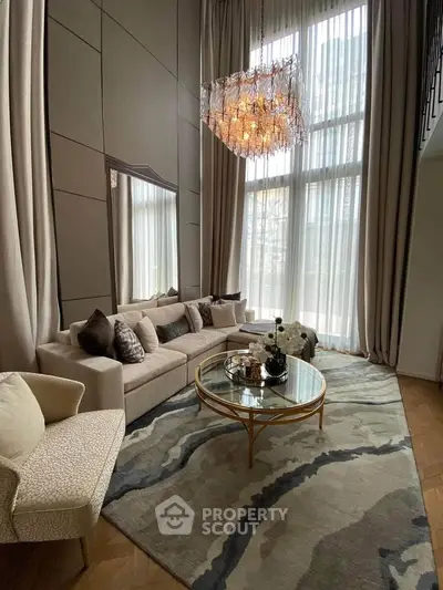 Luxurious living room with high ceilings, elegant chandelier, and plush seating in a modern apartment.