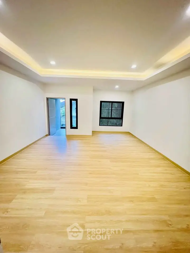 Spacious empty room with wooden flooring and recessed lighting, perfect for customization.