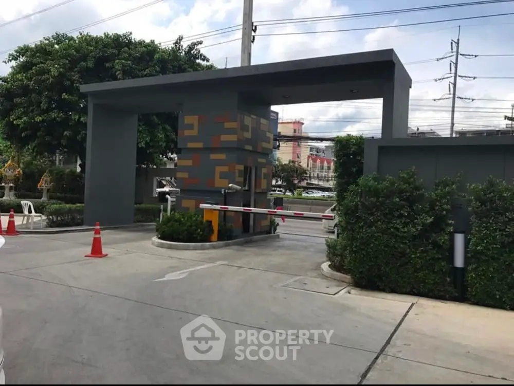 Modern gated entrance with security booth and barrier in residential complex.