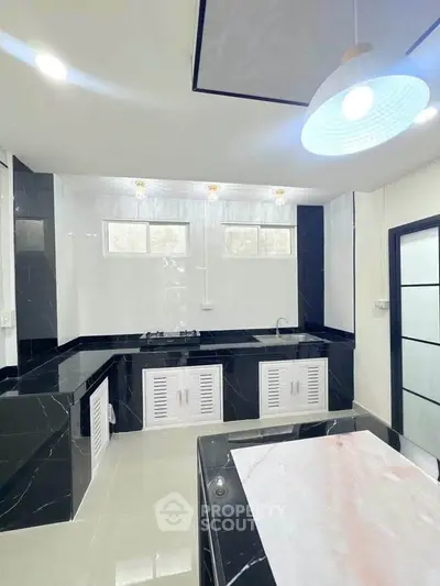 Modern kitchen with sleek black countertops and white cabinetry, featuring a gas stove and ample natural light.