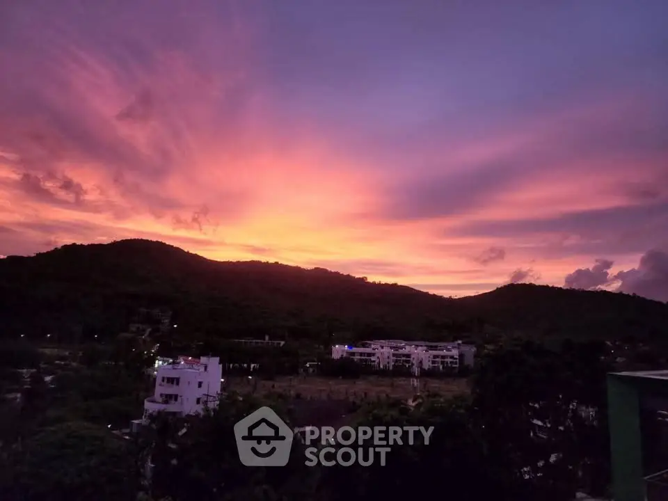 Stunning sunset view over lush hills and residential buildings, perfect for serene living.