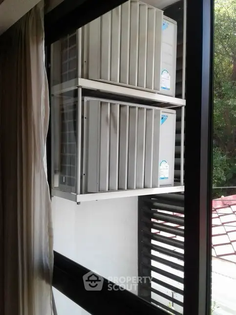 Window view of exterior air conditioning units in a residential setting.
