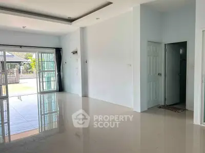 Spacious open-plan living area with glossy tiled floors and large windows for natural light.