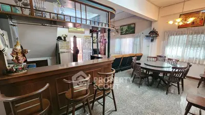 Charming open-plan living area with bar and dining set, perfect for entertaining.