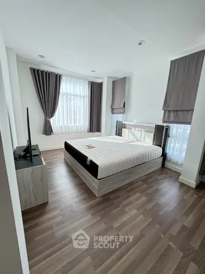 Spacious modern bedroom with large windows and elegant curtains