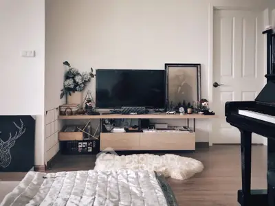 Elegant living space with grand piano, modern entertainment unit, and plush white rug, perfect for sophisticated urban living.