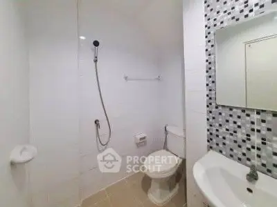 Modern bathroom with sleek white tiles and stylish mosaic accent wall.