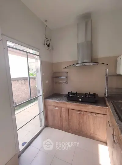 Modern kitchen with gas stove and outdoor access, featuring sleek cabinetry and ample natural light.