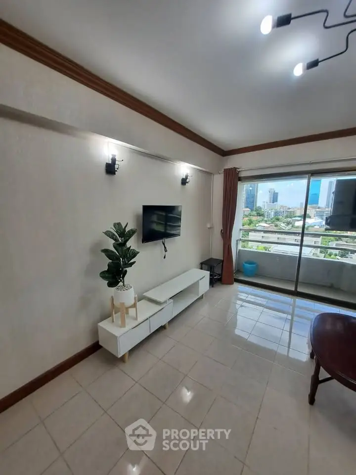 Spacious living room with modern decor and city view balcony in high-rise apartment.