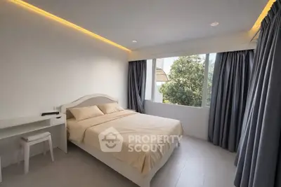 Modern bedroom with large windows and elegant curtains, featuring a cozy bed and minimalist decor.