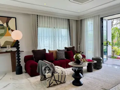 Luxurious living room with modern decor and garden view, featuring elegant furniture and large windows.