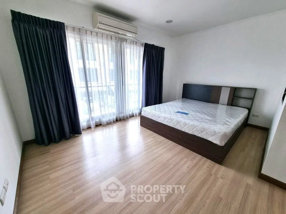 Spacious bedroom with large window and modern furnishings in a stylish apartment.