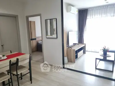 Modern living room with sleek furniture and natural light, featuring a stylish dining area and cozy bedroom view.