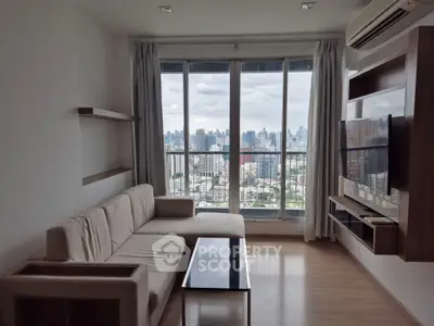 Modern living room with city view, featuring sleek furniture and large windows.
