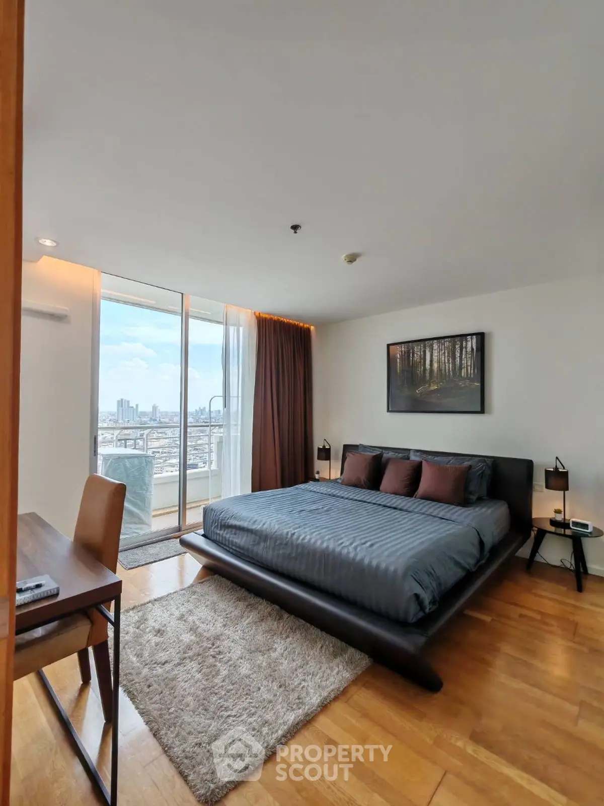 Spacious bedroom with city view and modern decor in high-rise apartment.