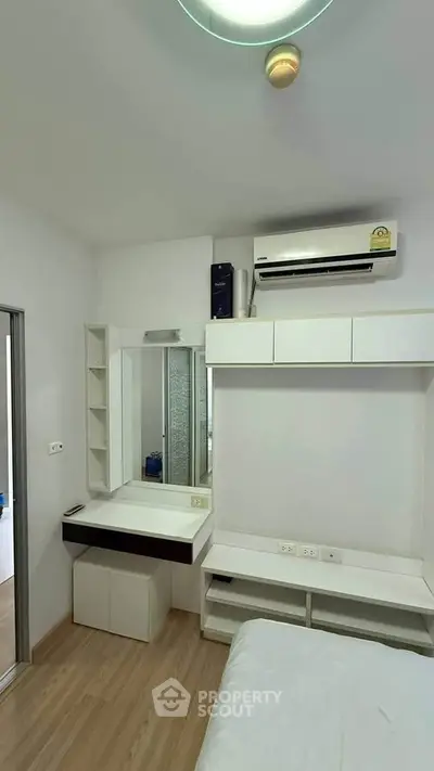 Modern bedroom with built-in storage and air conditioning, featuring sleek design and efficient use of space.