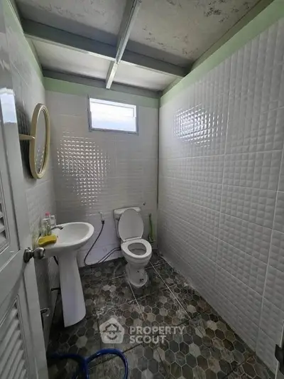 Compact bathroom with modern tiles and natural light from window.