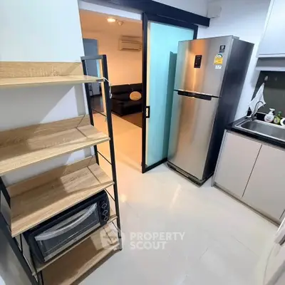 Modern kitchen with stainless steel fridge and microwave, open layout to living room.