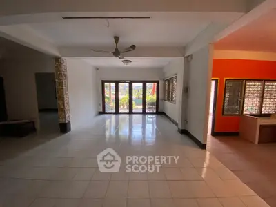 Spacious open-plan living area with large windows and tiled flooring