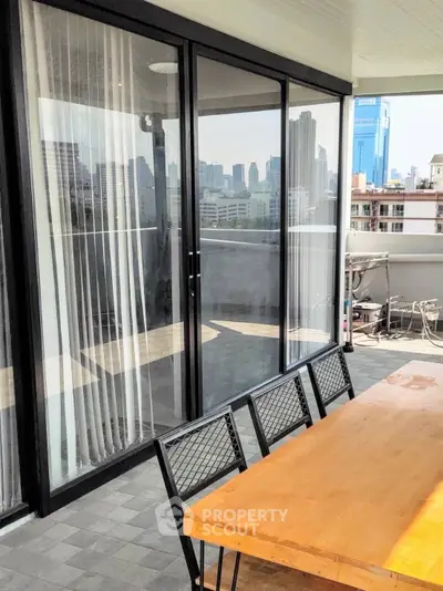 Spacious balcony with city view, perfect for outdoor dining and relaxation in urban setting.