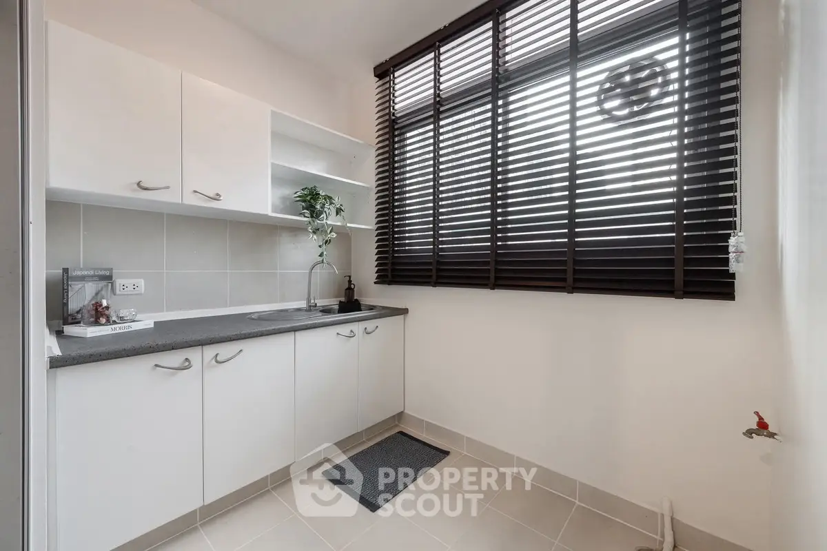 Modern kitchen with sleek cabinetry and large window blinds