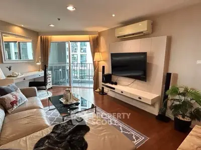 Modern living room with balcony, stylish decor, and large TV in urban apartment.