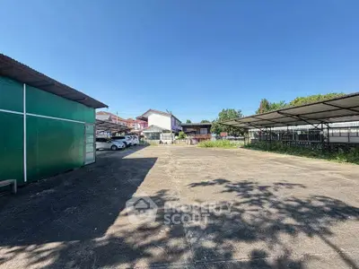 Spacious outdoor parking area with covered spaces and clear blue sky.