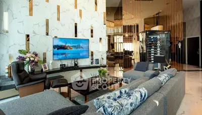 Luxurious living room with modern decor, large TV, and elegant seating area.