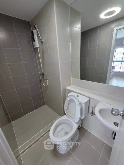 Modern bathroom with sleek tiles and shower area in contemporary apartment.