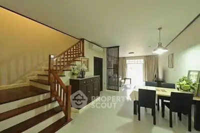 Spacious open-plan living and dining area with modern staircase and elegant decor.