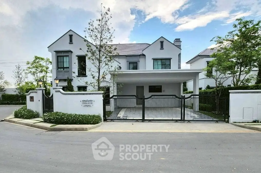 Elegant modern house with gated entrance and lush landscaping in a serene neighborhood.