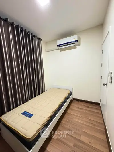 Cozy minimalist bedroom with single bed and air conditioning, ideal for compact living spaces.
