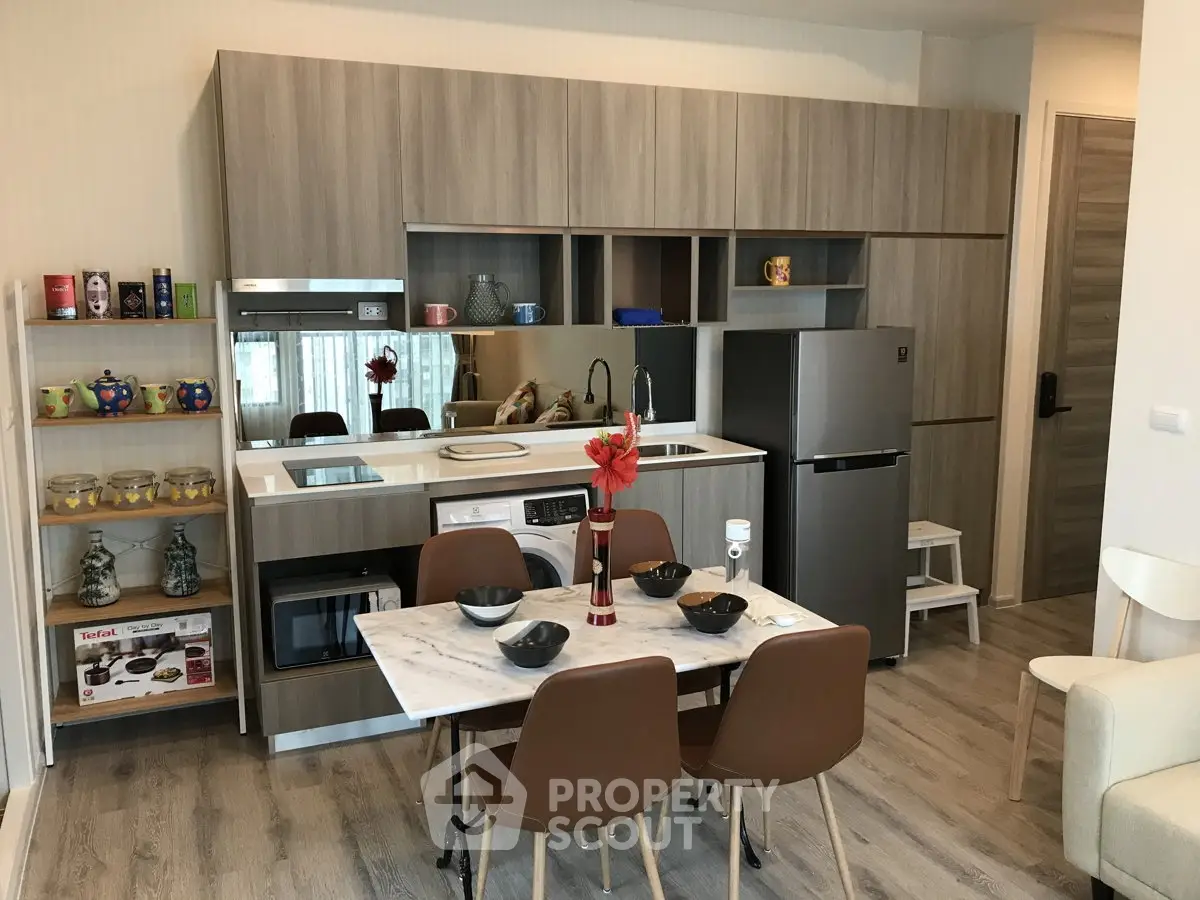 Modern kitchen with sleek cabinetry, marble dining table, and stainless steel appliances in stylish apartment.