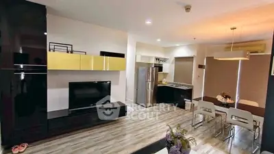 Modern open-layout living room with sleek kitchen and dining area, featuring stylish decor and contemporary appliances.