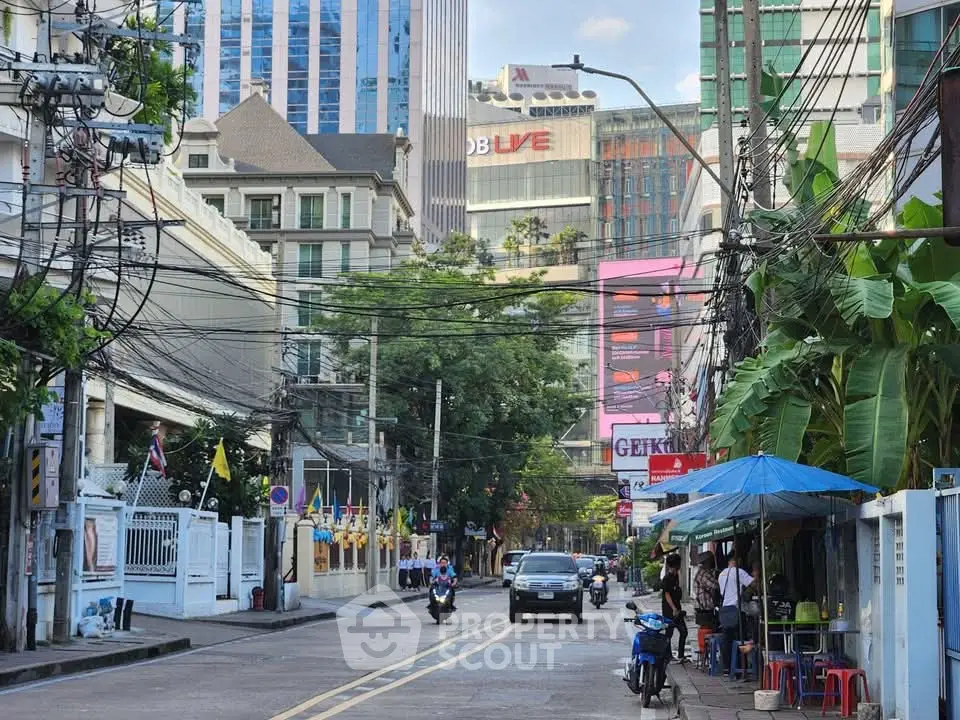 Urban street view with high-rise buildings and local shops, showcasing vibrant city life.